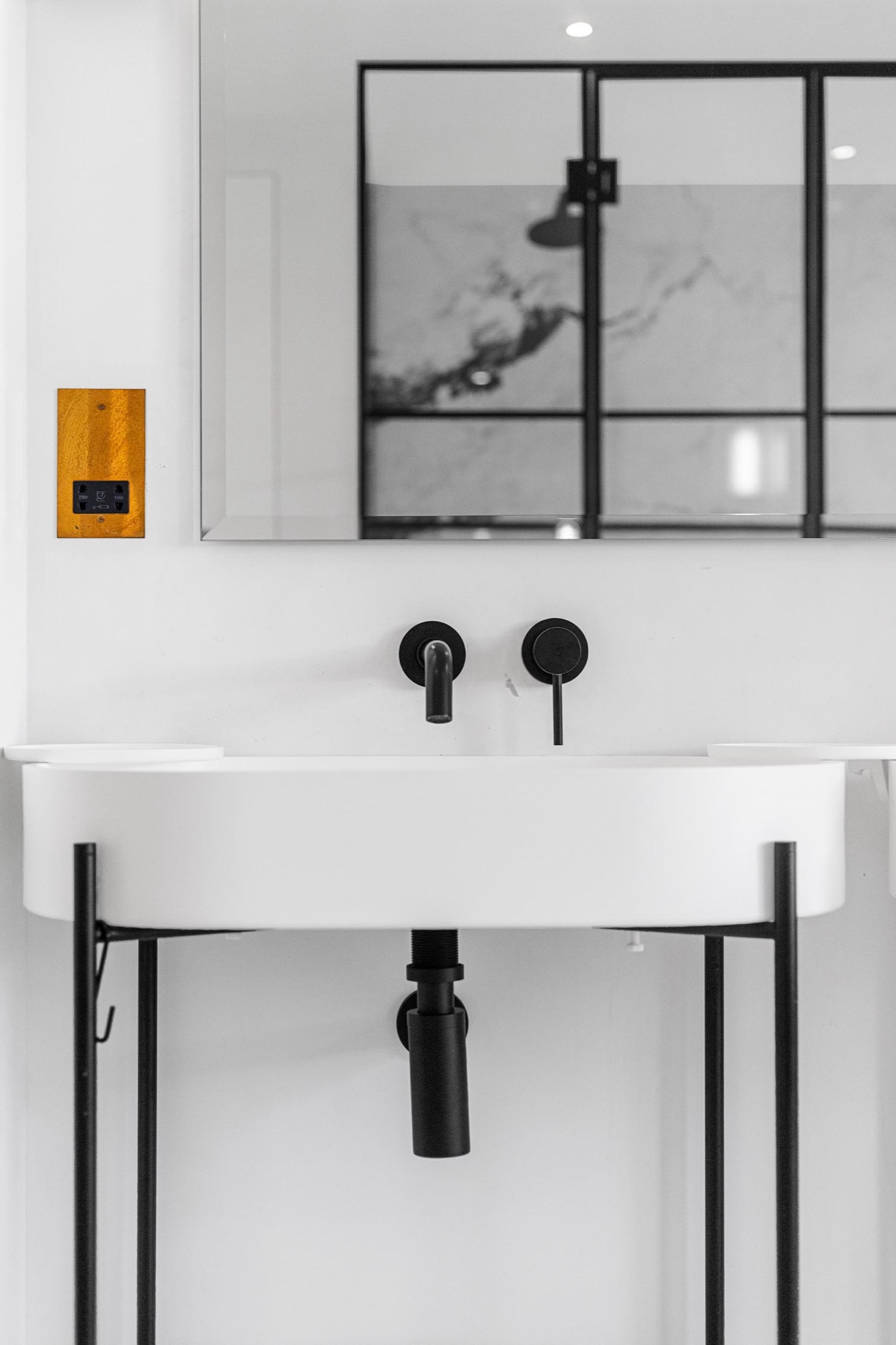 Bathroom detail photography in a Marylebone flat: wall-hung basin with black taps and steel-framed mirror