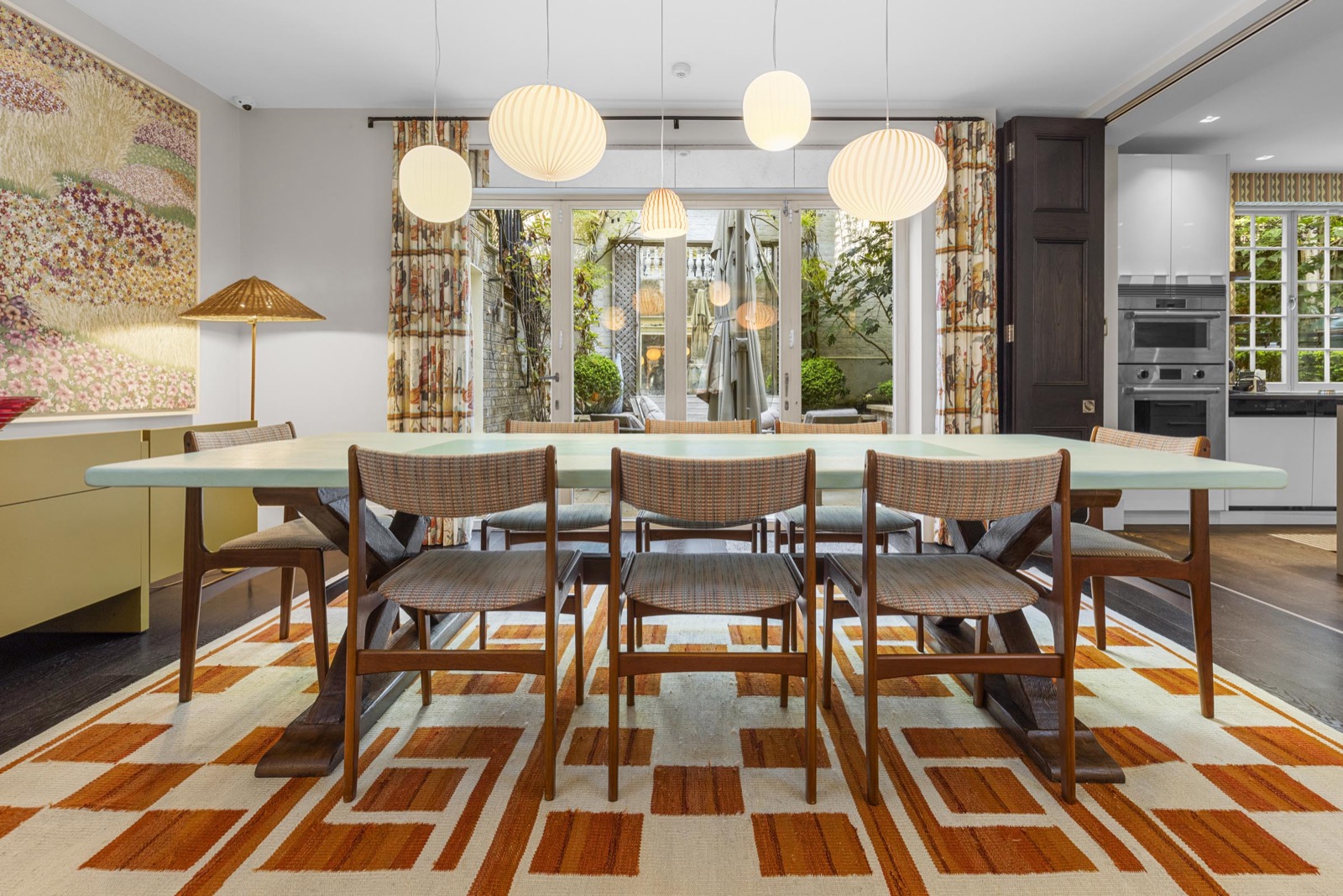 Dining room photography in Holland Park: walnut table, paper lanterns and graphic rug by the garden doors
