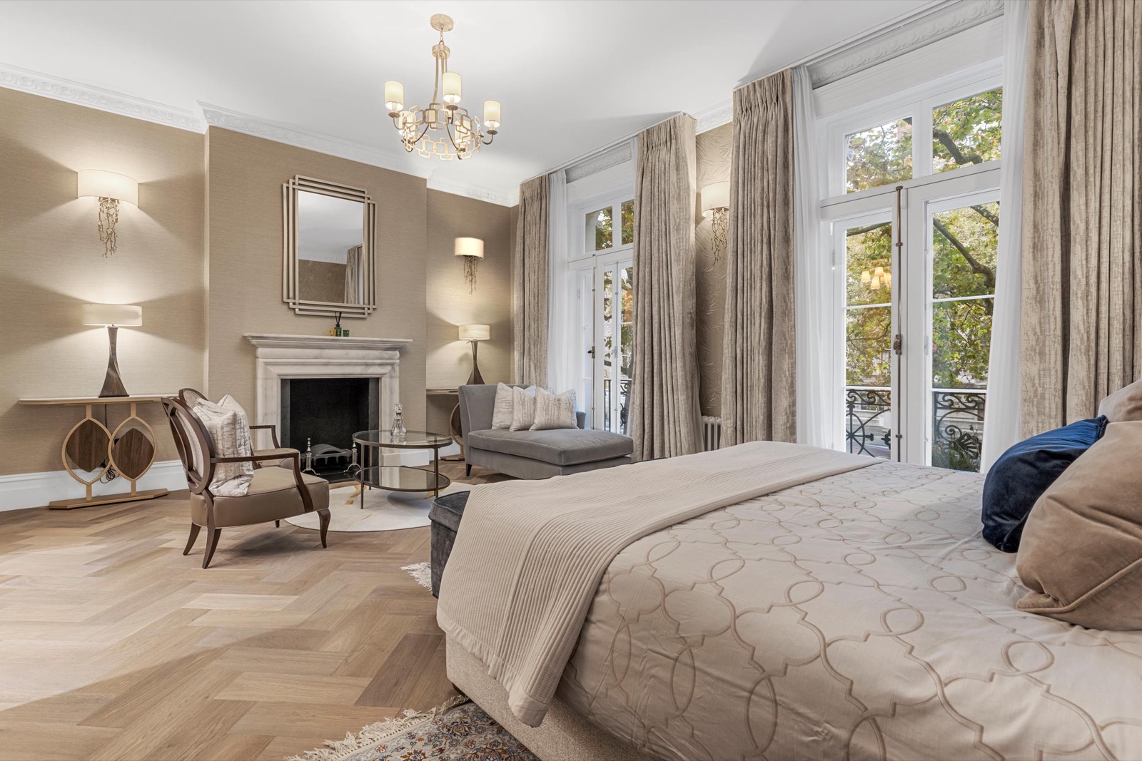 Bedroom photography in a Chelsea house: marble fireplace, chandelier and tall garden windows in soft light