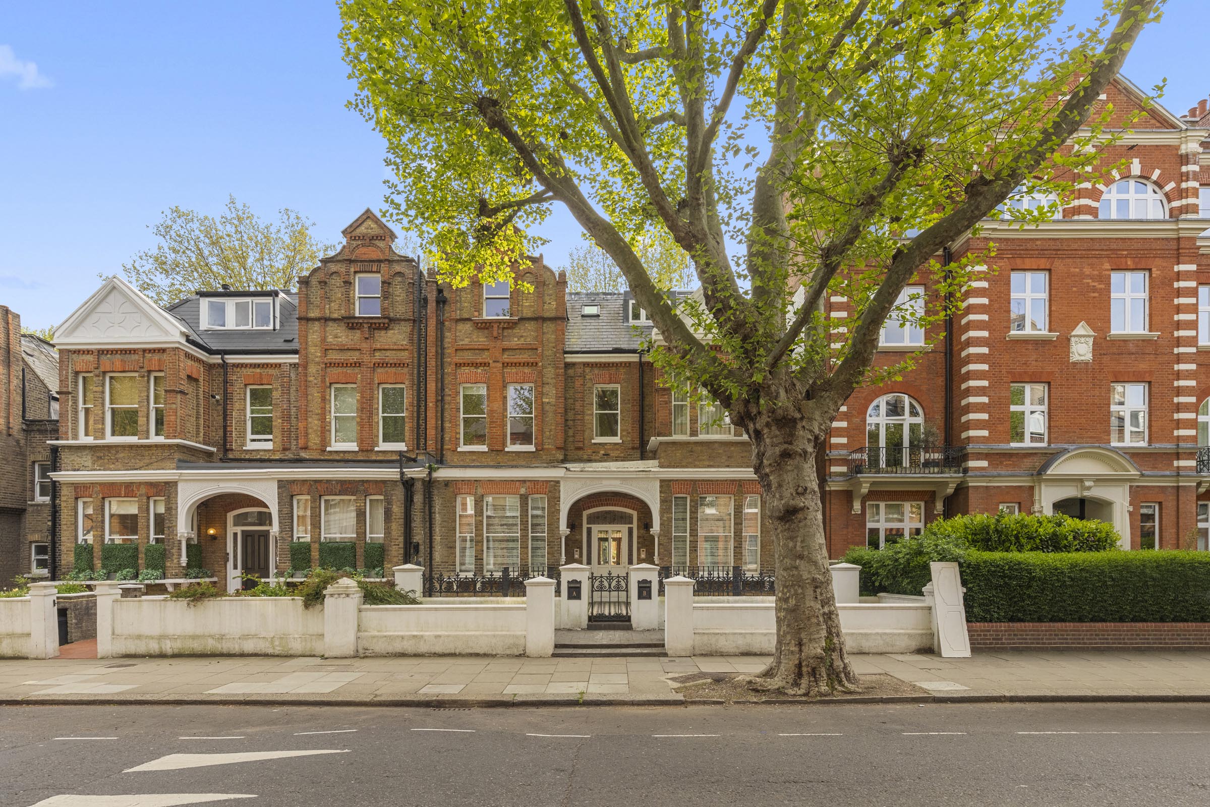 Red-brick mansion houses on a tree-lined London street, photographed by Finest Spaces