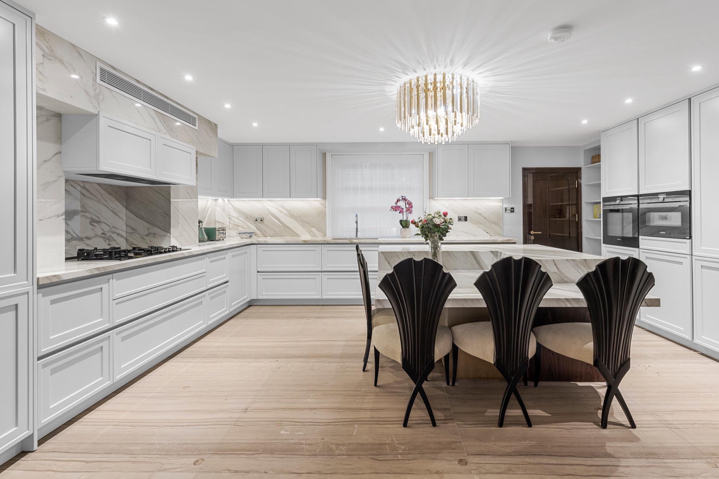 Kitchen photography in a St John's Wood house: handleless white cabinetry, marble and crystal chandelier